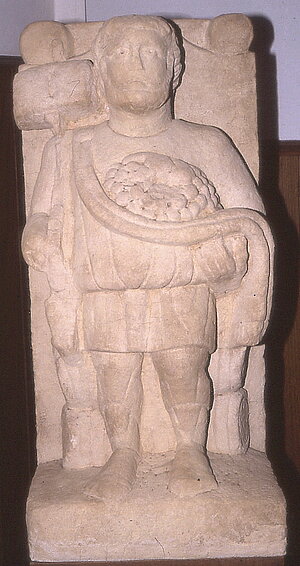 Einfarbige Statue, die eine stehende Person mit Weintrauben zeigt