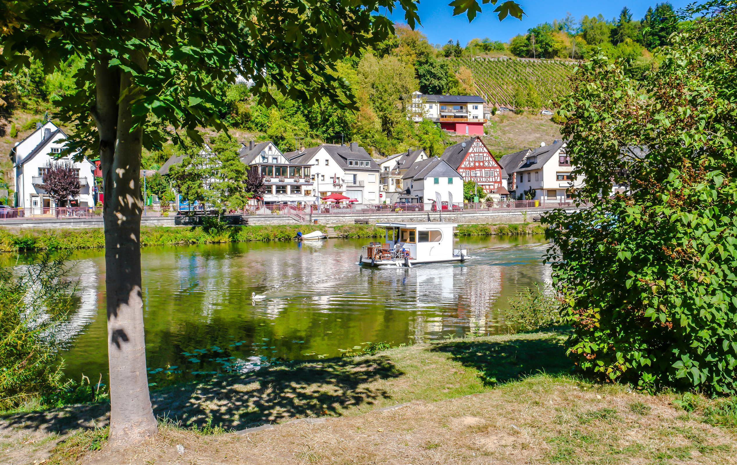 Idyllische Lahn mit Hausboot und Häusern in Obernhof, traditionelle Weinregion.